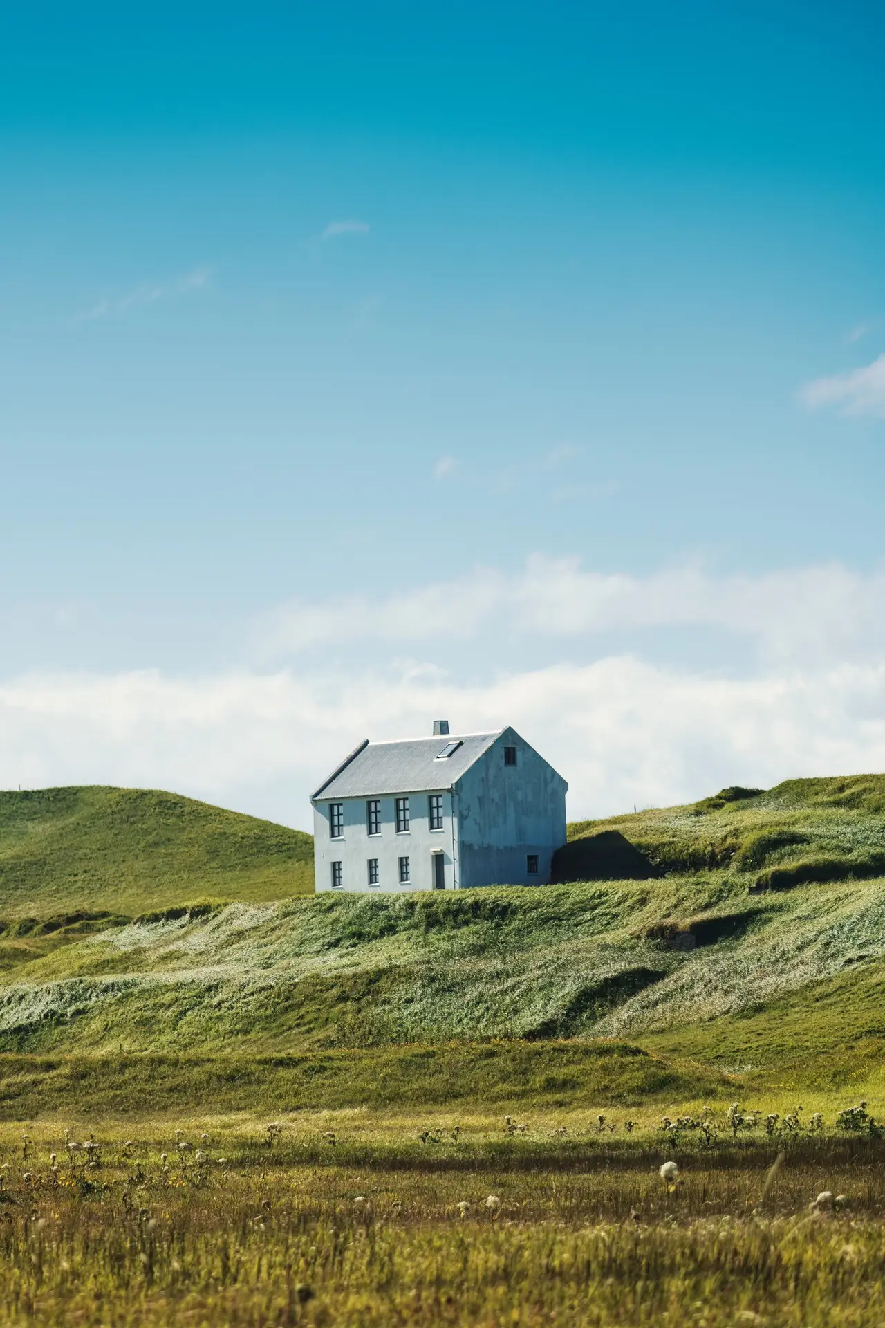 Nordic house on hill among the farmland in countryside on bright day at Iceland